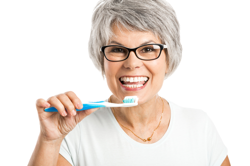 Portrait of a happy older woman brushing her teeth to prevent tooth loss