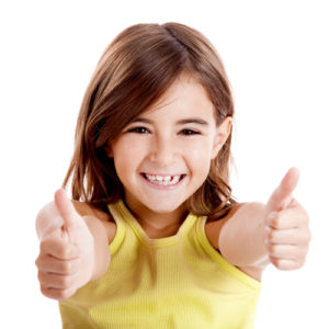 child smiling with two thumbs up showing healthy smile