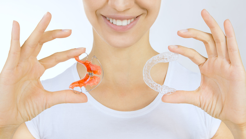 girl holding retainer for teeth (dental braces) and individual tooth tray