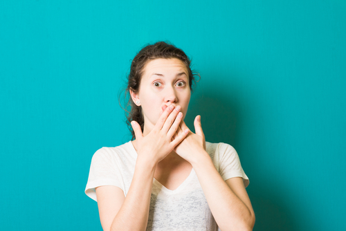 girl covers white spots on her teeth with her hands