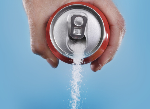 hand holding soda can pouring sugar