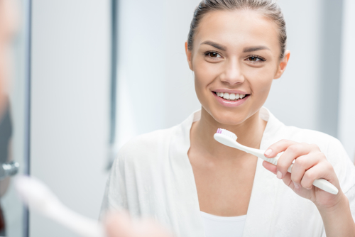 woman looking in the mirror with toothbrush in hand